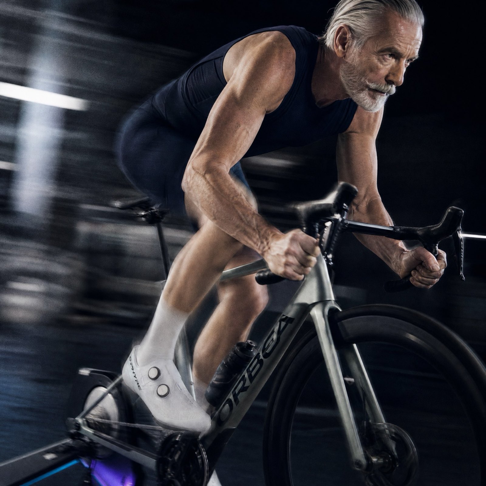 A grey-haired rider low on the bars of an indoor trainer, the room blurred past him.